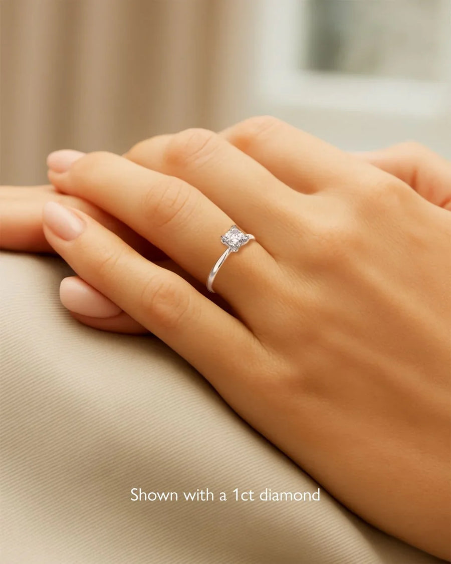 Hand wearing an elegant solitaire diamond engagement ring with a 1ct diamond on a simple band