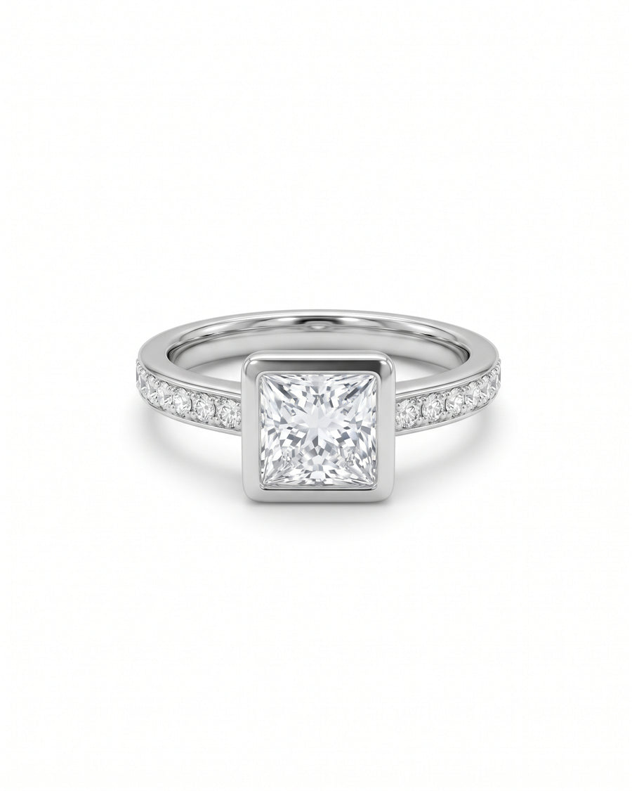 Princess cut diamond engagement ring in a silver-tone bezel setting with pavé diamonds on the band.