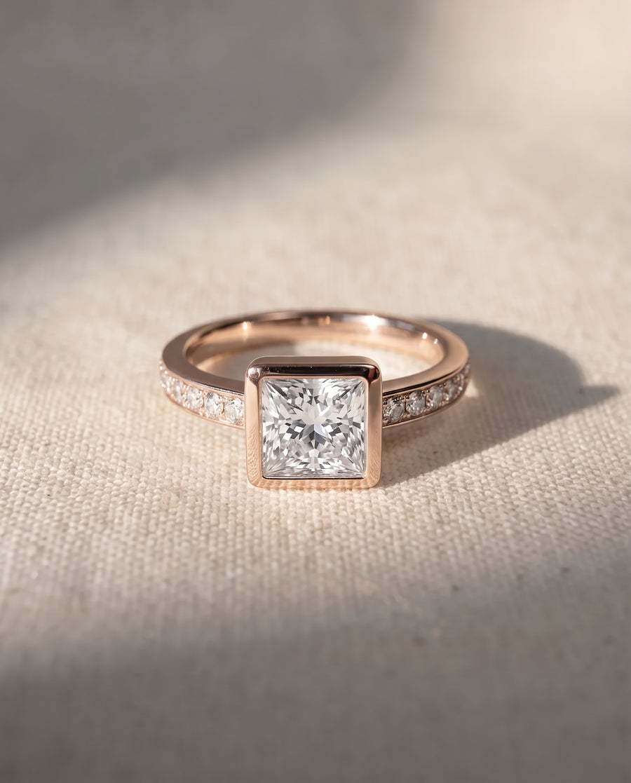 Princess cut diamond engagement ring in 18ct rose gold with a bezel setting and pavé diamond band.
