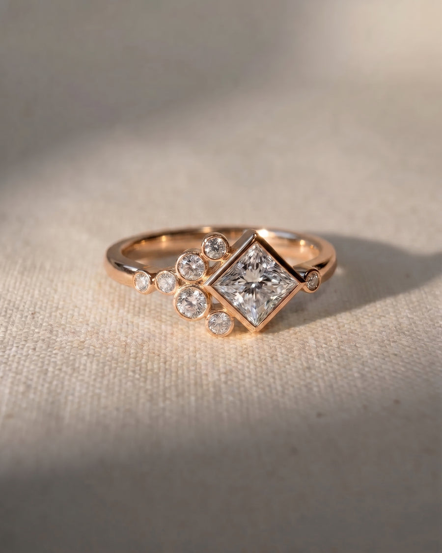 18ct rose gold engagement ring with a princess cut diamond and round accent diamonds.
