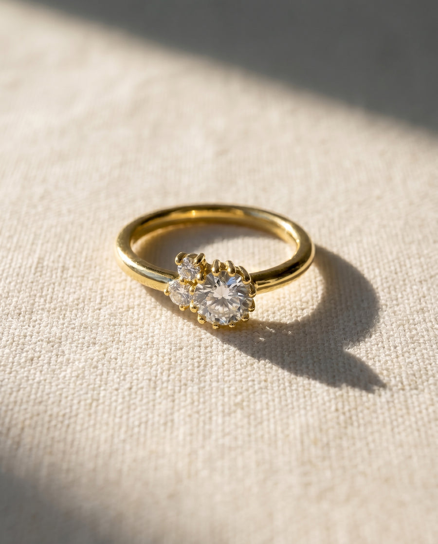 Gold engagement ring with a random claw cluster of round diamonds.