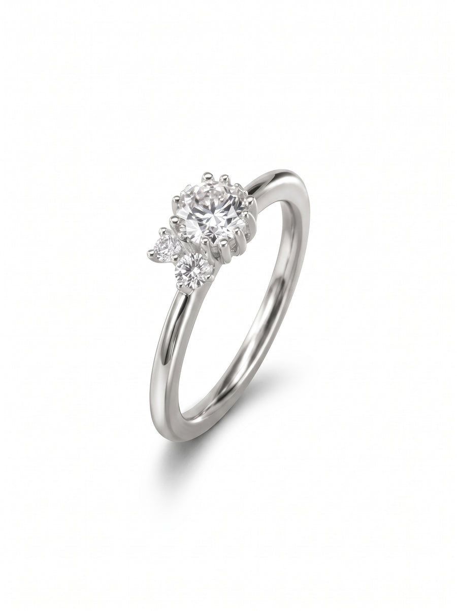 Silver engagement ring with a cluster of three round-cut diamonds in a claw setting on a smooth band.