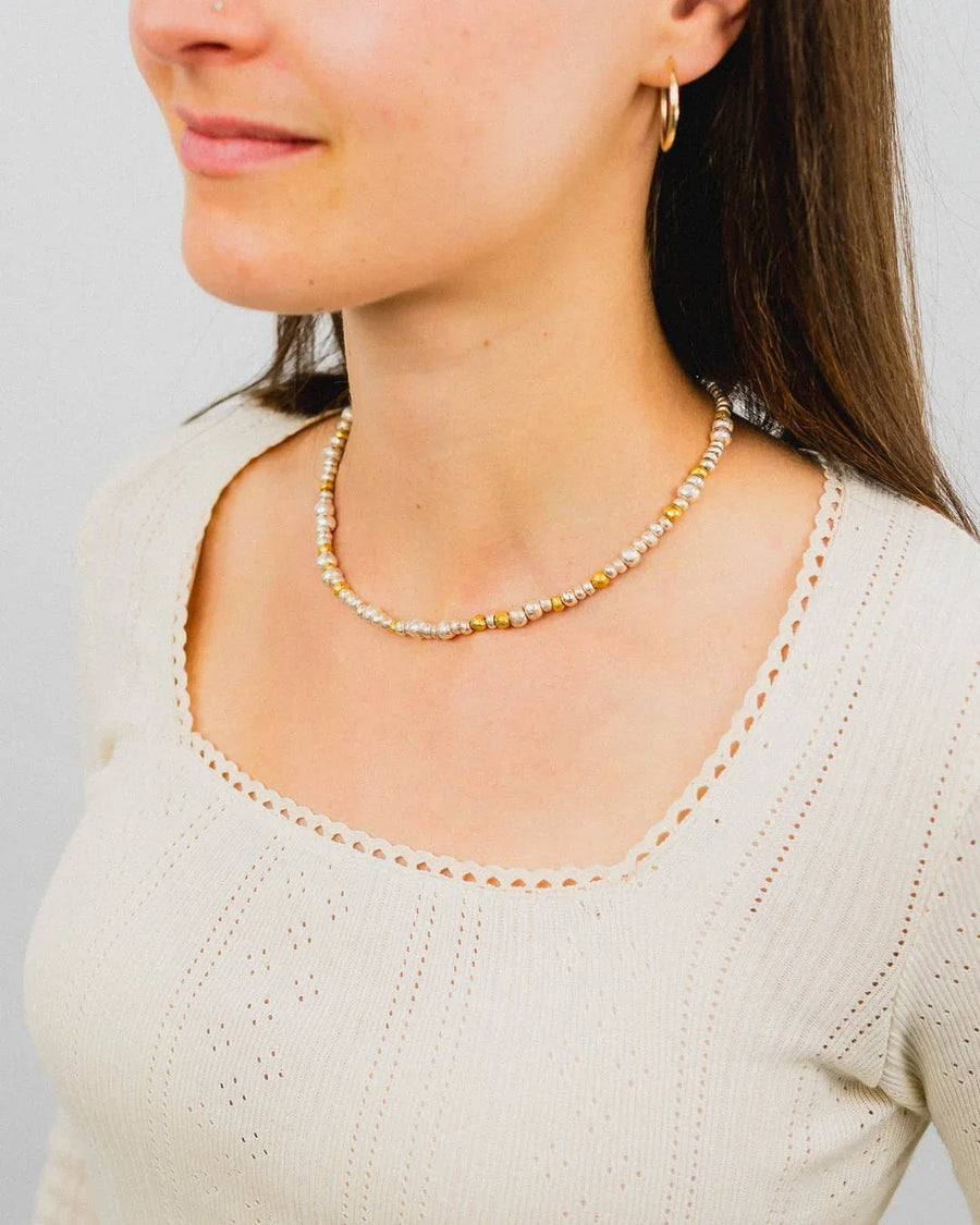 Woman wearing a beaded silver and gold nugget necklace with organic texture