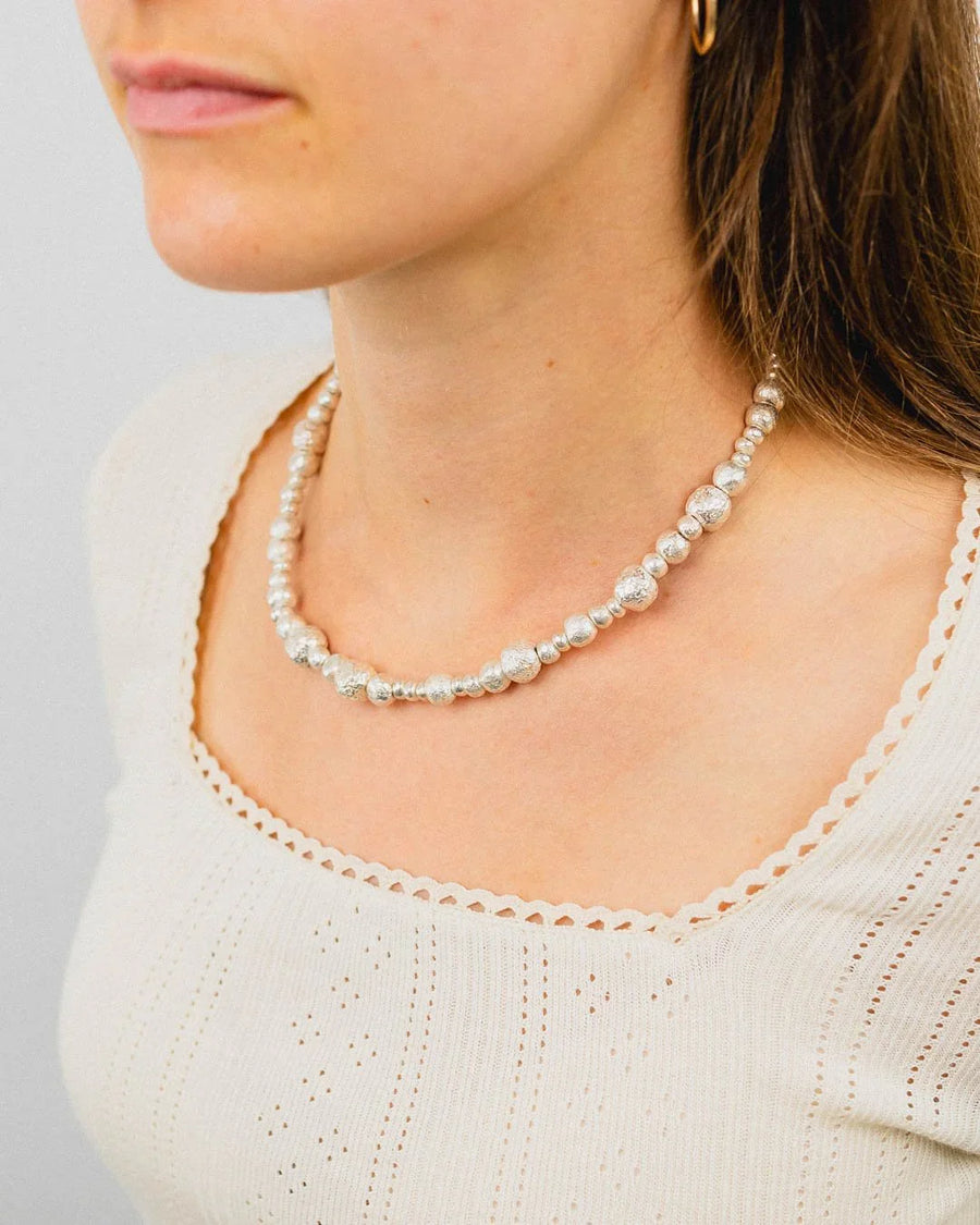 Textured silver nugget necklace with organic beads worn by woman in cream top