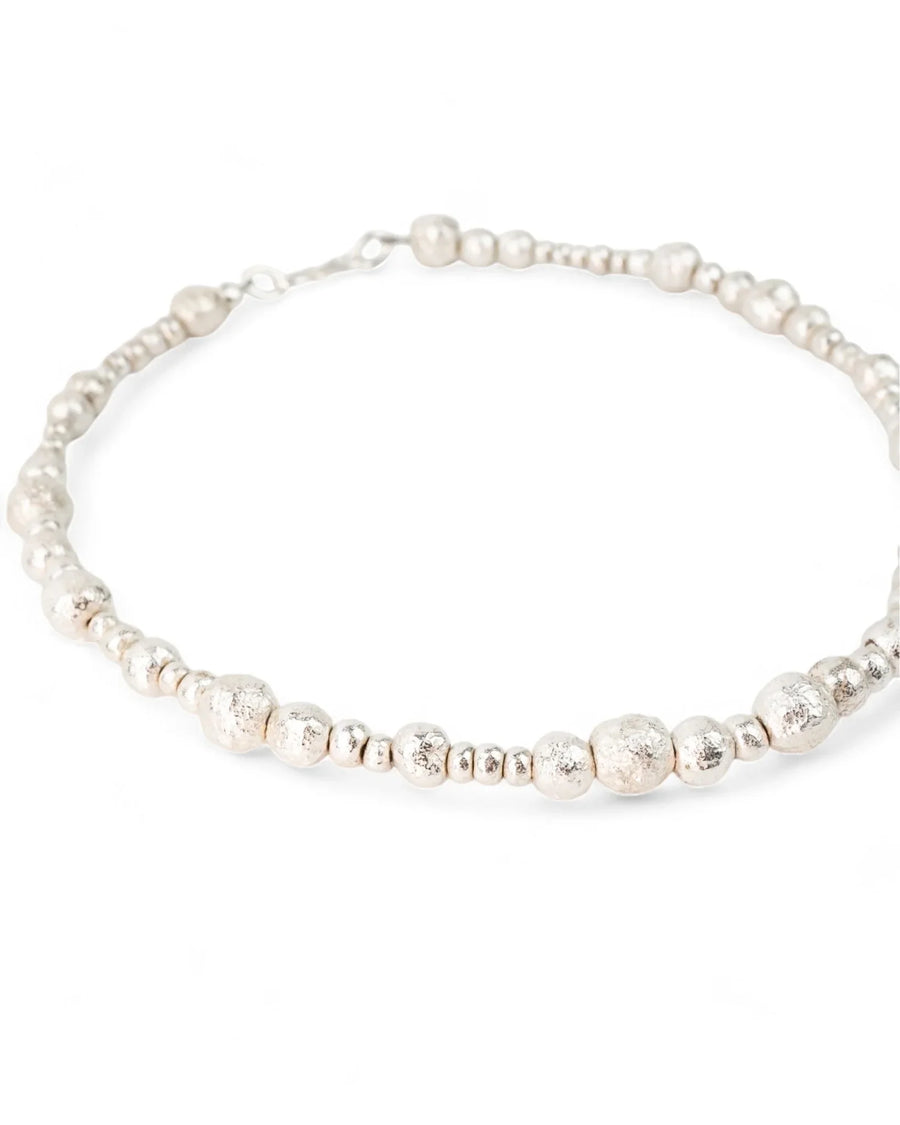 Handmade silver necklace with organic, textured nugget beads on a white background