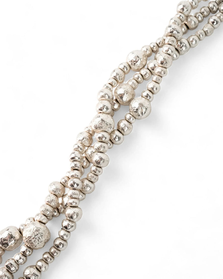 Triple strand silver nugget bead bracelet with organic, textured finish on white background.