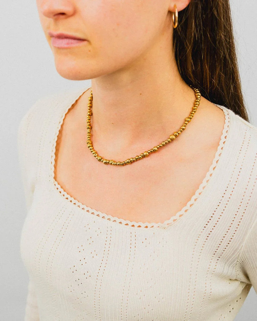 Yellow gold nugget bead necklace with organic texture, worn by woman in cream top