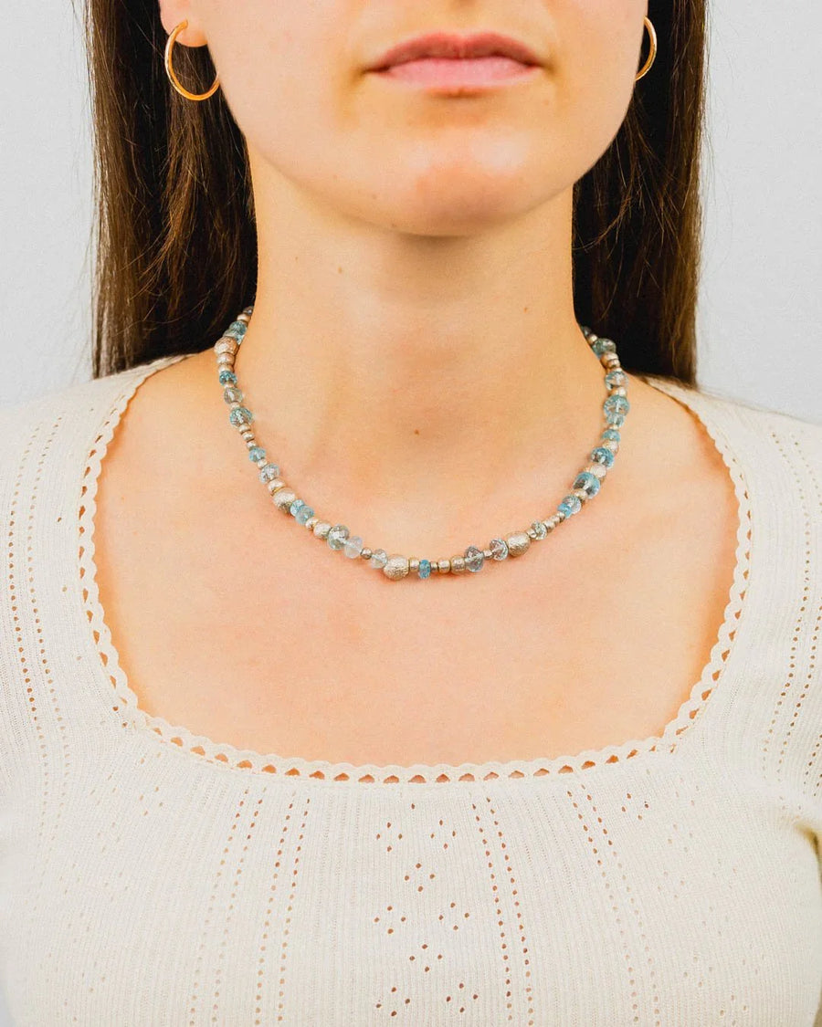 Woman wearing a handmade silver nugget and blue topaz necklace with organic shapes