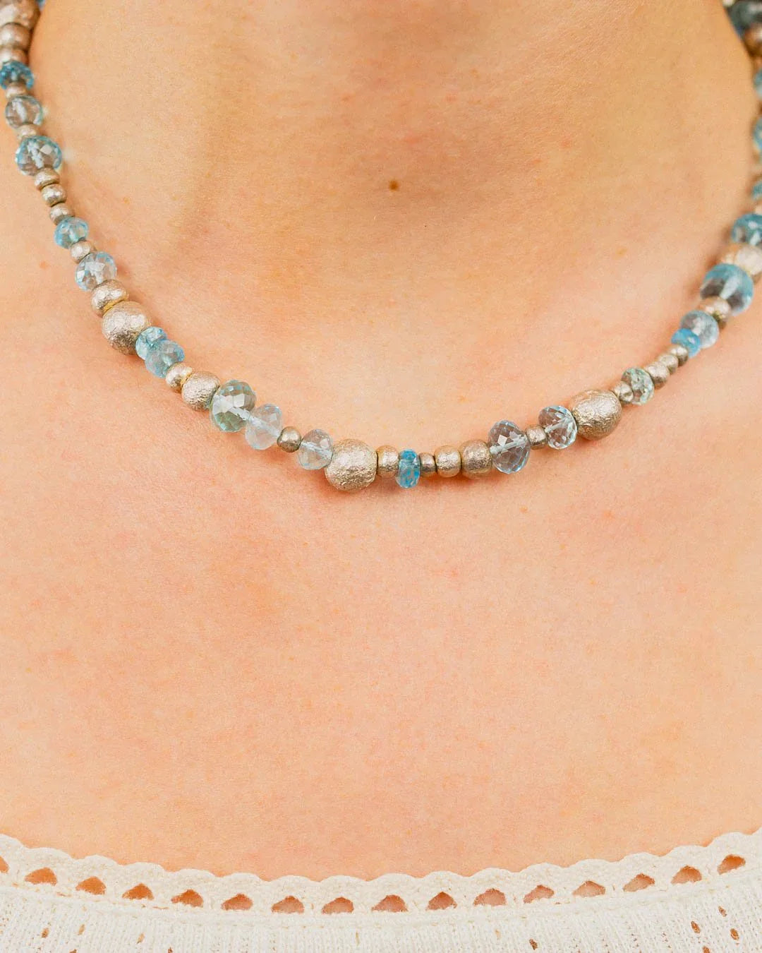 Silver nugget and blue topaz beaded necklace on a woman's neck, handmade jewellery