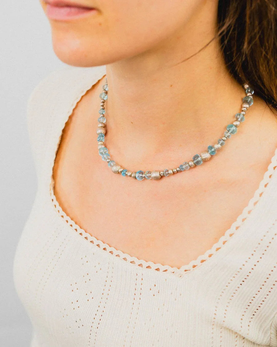 Woman wearing a handmade necklace with organic silver nuggets and blue topaz beads