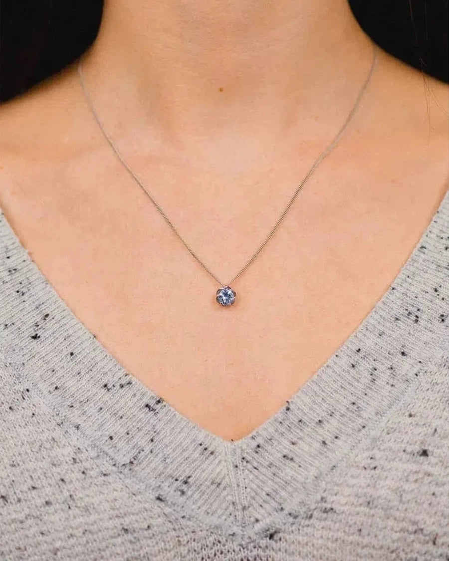 White gold pendant necklace with round aquamarine stone on model's neck