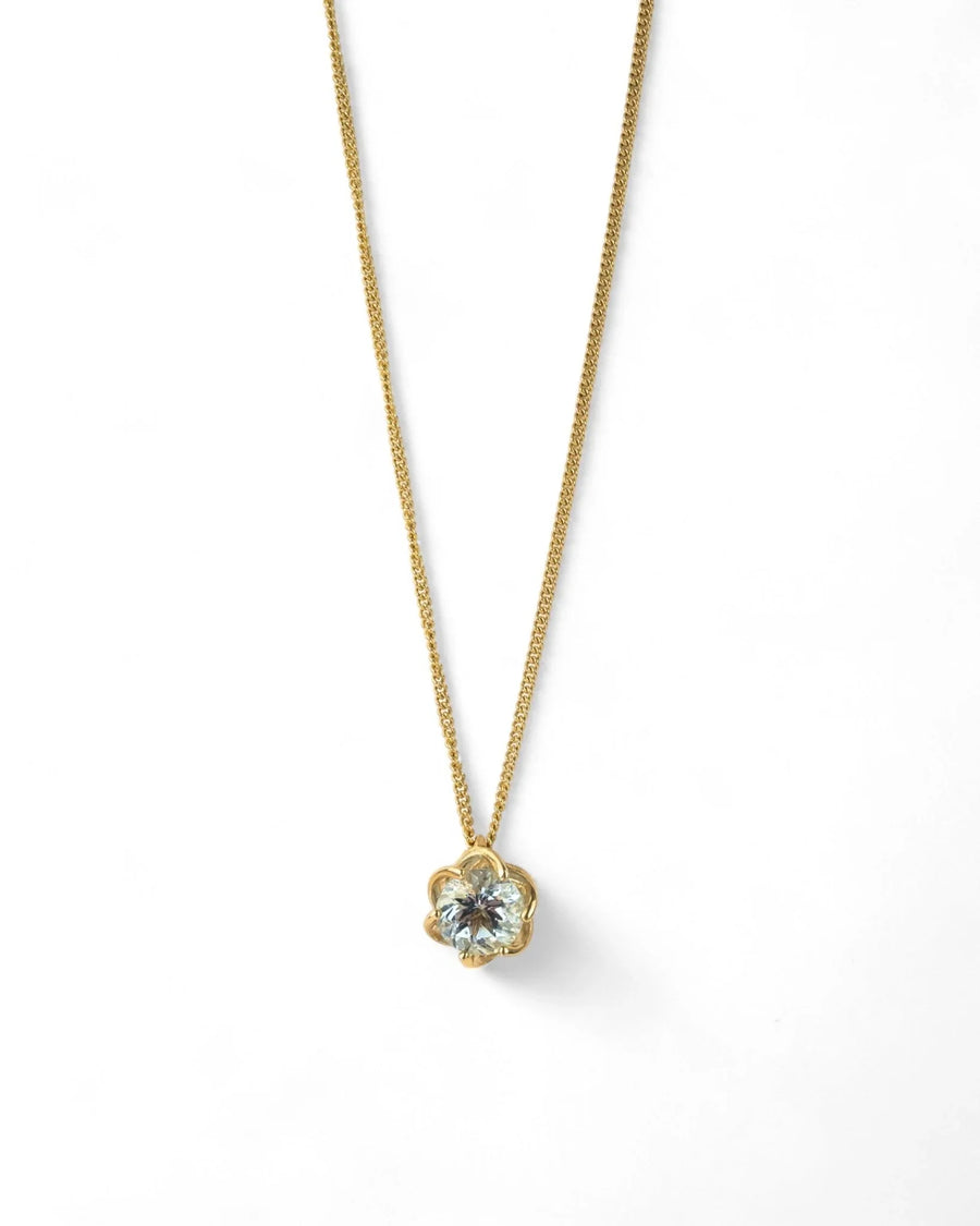 Yellow gold chain with aquamarine claw-set pendant on white background