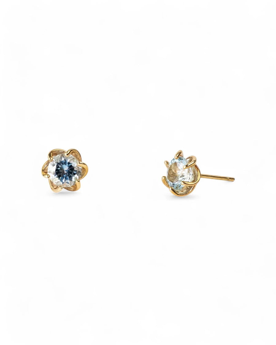 Gold revolved claw stud earrings with light blue gemstones.