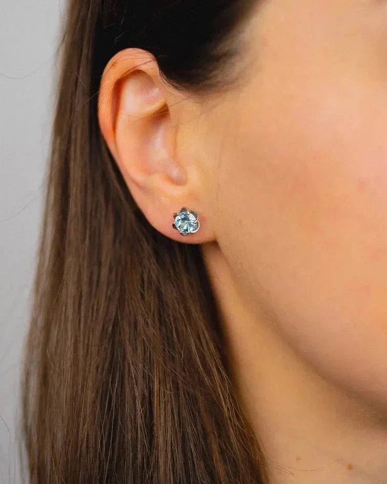 Silver revolved claw stud earring with a light blue gemstone.