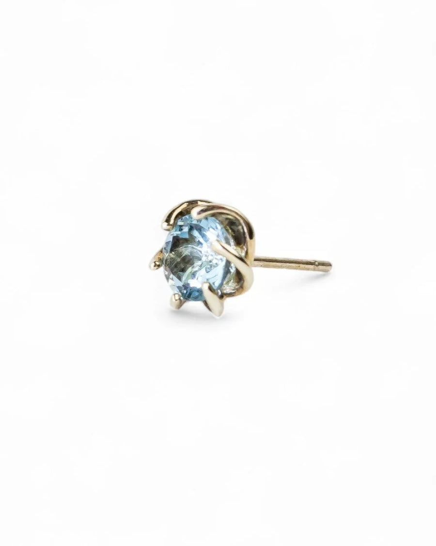 Gold revolved claw stud earring with a light blue gemstone.