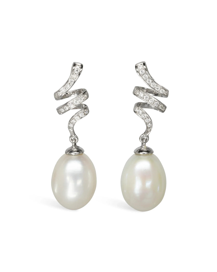 Sculpted swirl earrings with pavé diamonds and large pearl drops on a white background