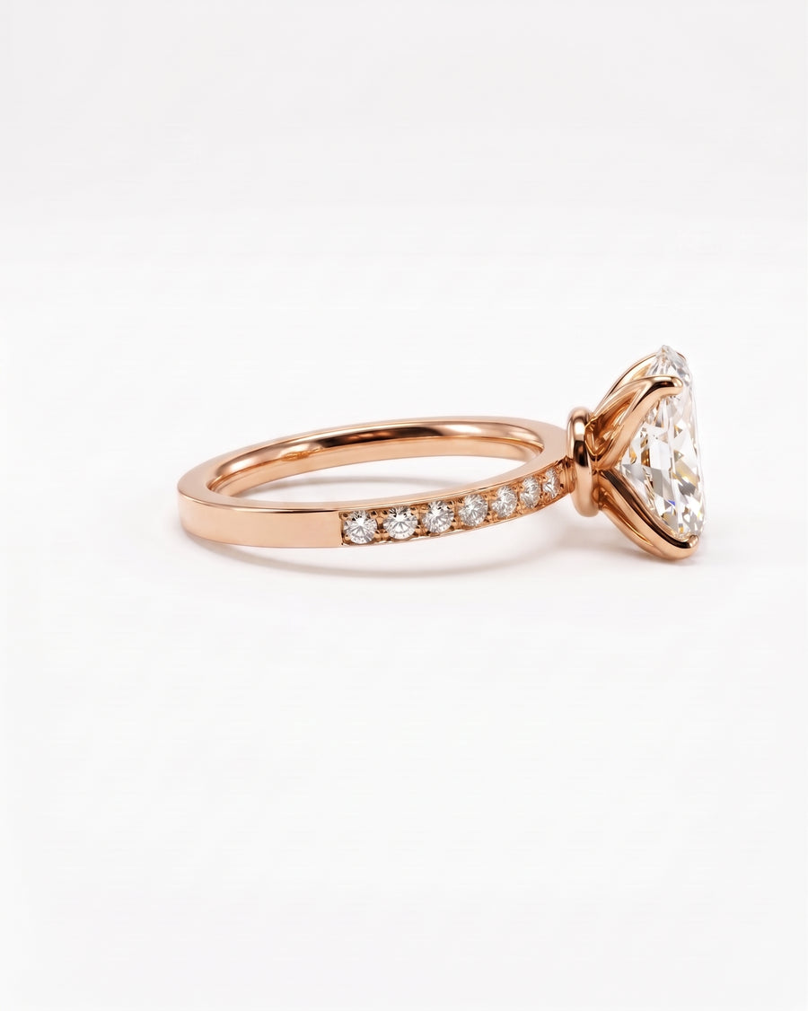 A rose gold engagement ring featuring a large triangular clear gemstone in a prong setting, with a pavé band of small round diamonds, shown on a clean white background.