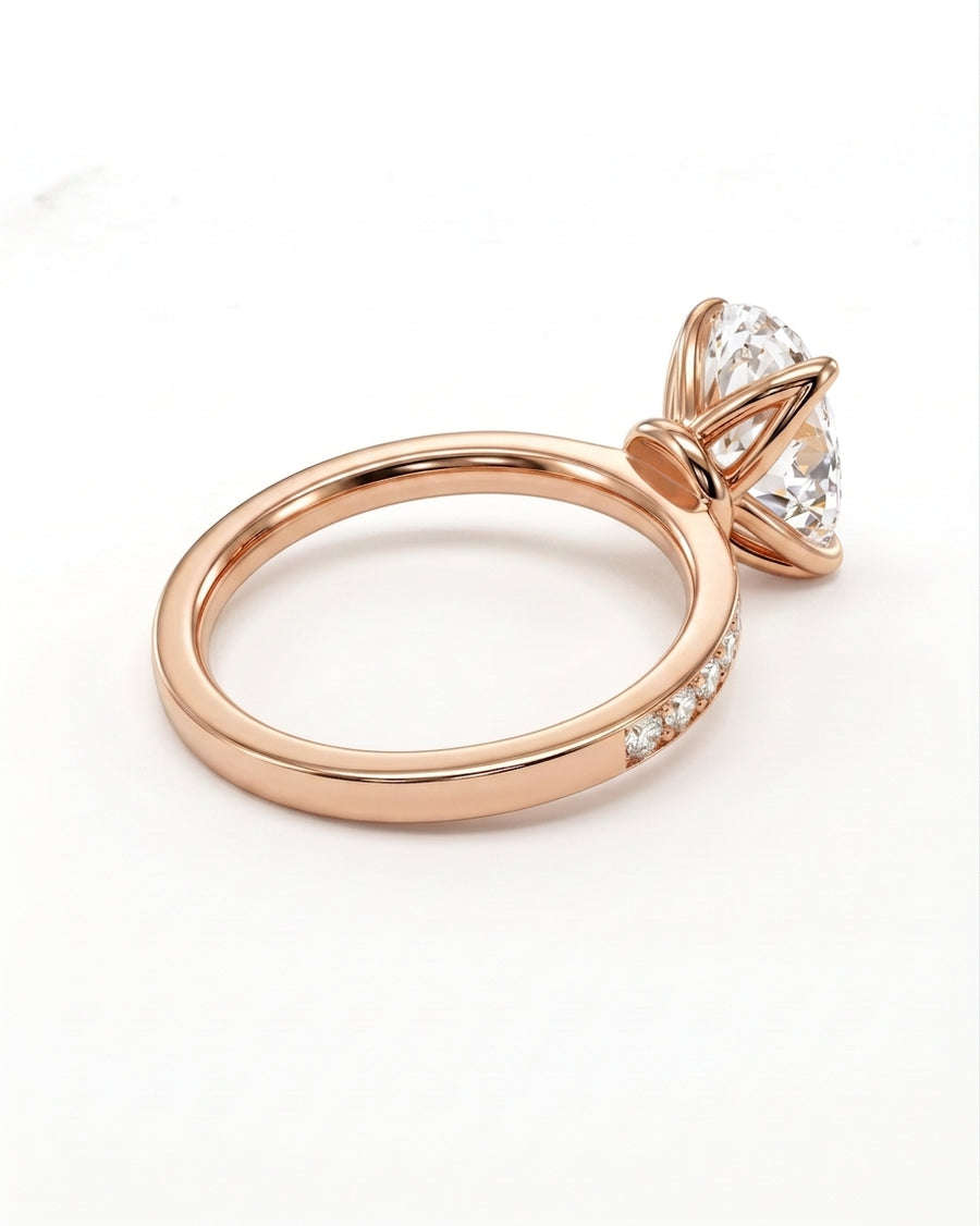 Rose gold ring with a large clear round-cut gemstone in a prong setting and small accent stones along the band, photographed on a clean white background.