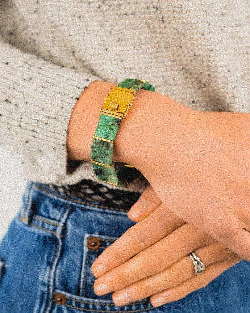Rough Brazilian emerald bracelet with gold clasp on wrist, paired with jeans and knit sweater