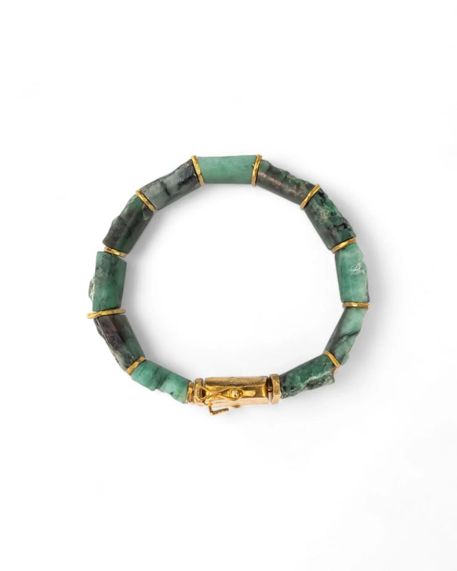 Rough Brazilian emerald bracelet with chunky green stones and gold accents on white background