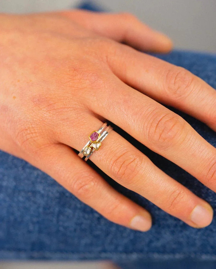Hand wearing a silver rough cut ruby stacking ring set with organic, textured design