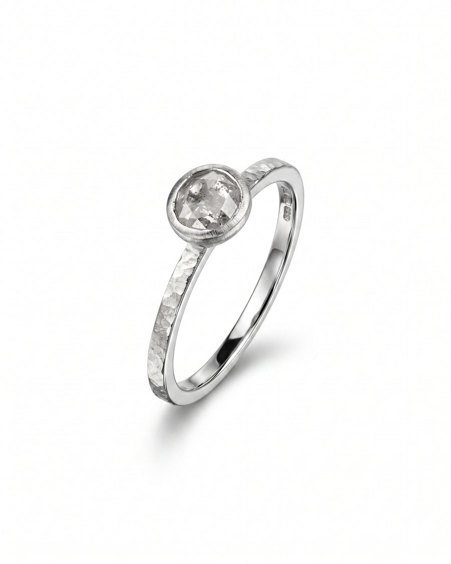 Silver ring with a round rough diamond in a bezel setting.