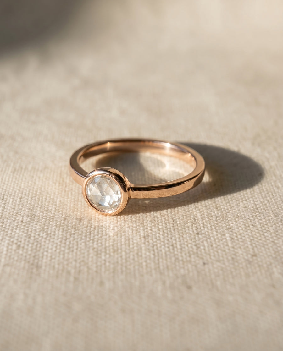 Rose gold engagement ring with a bezel-set, oval rough diamond.