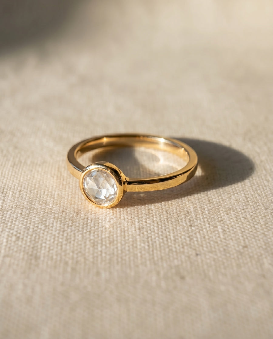 Gold ring with a bezel-set oval rough diamond.