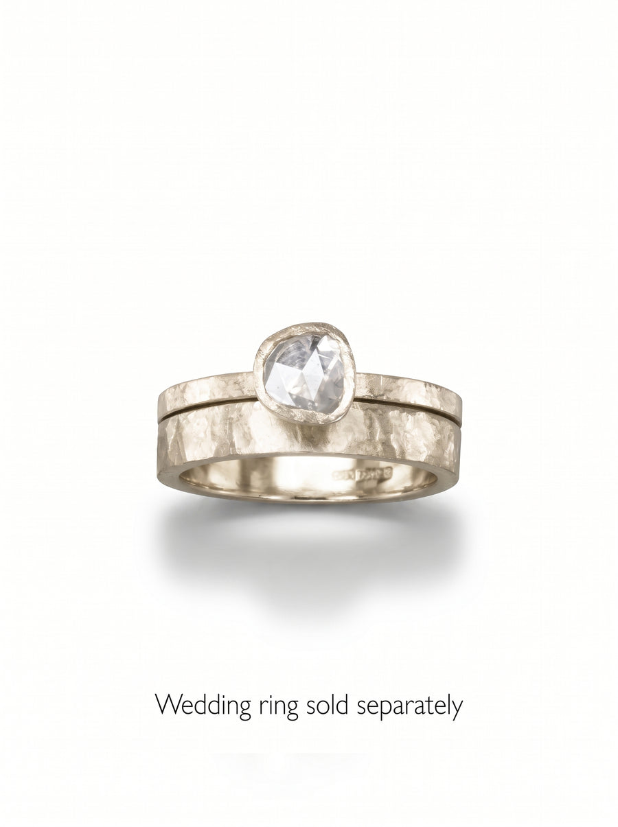 Rough diamond engagement ring with a hammered gold band and a bezel-set rose cut diamond.