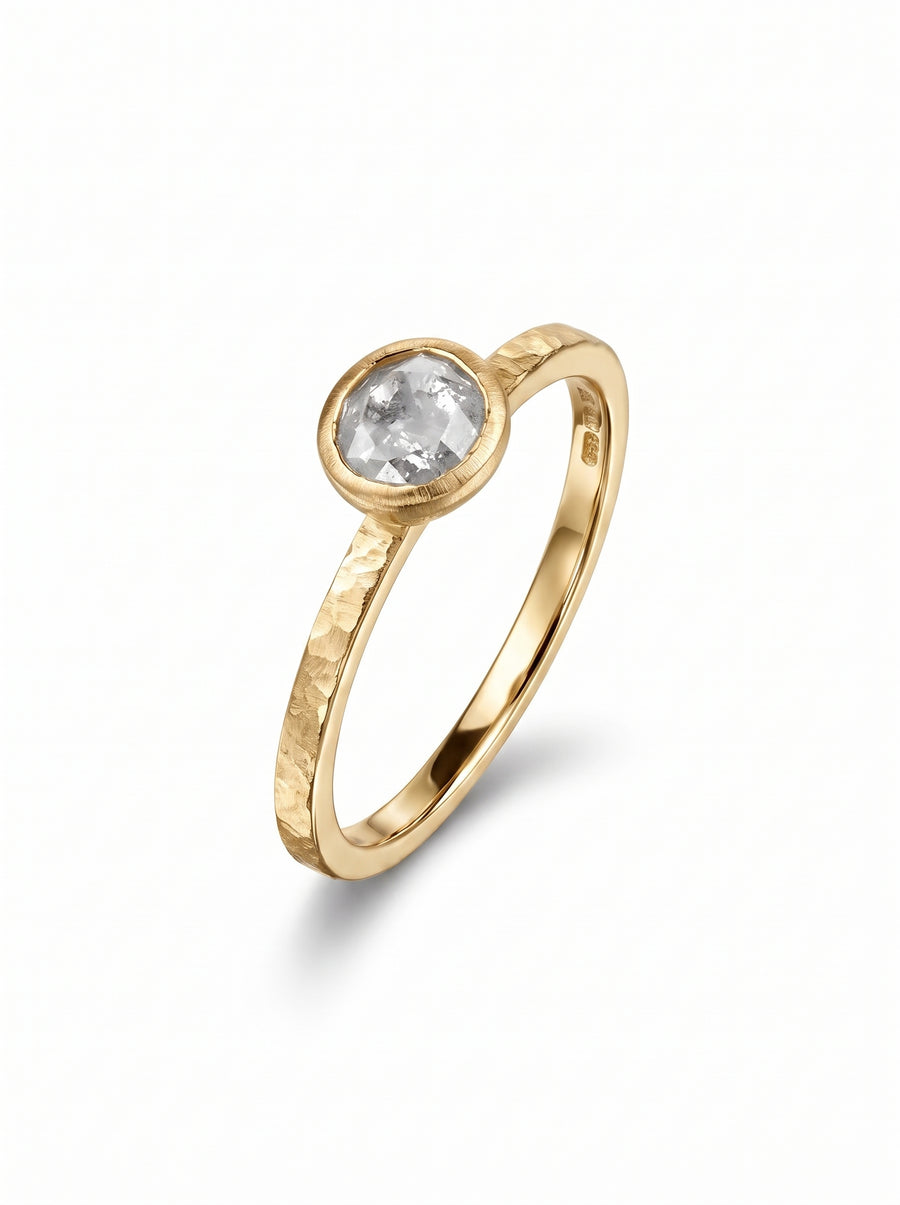Gold ring with a bezel-set rough diamond and a textured, hammered band finish.