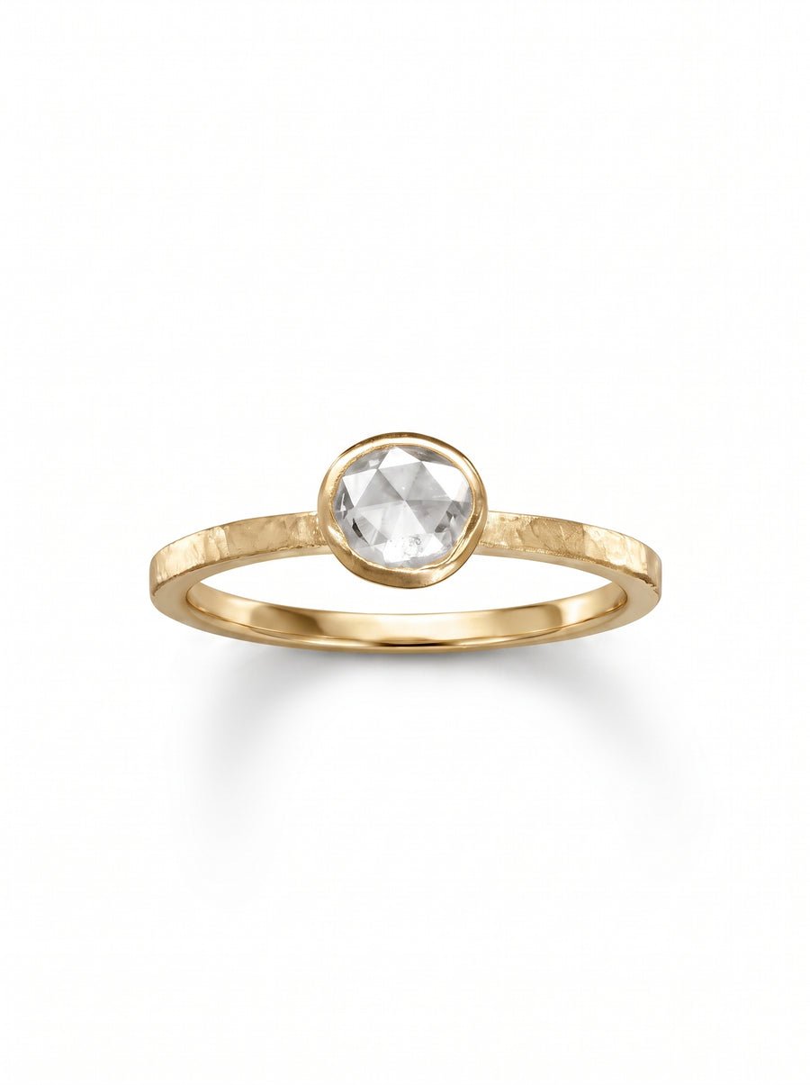 Rough diamond engagement ring with a round rose-cut stone set in a textured yellow gold band.