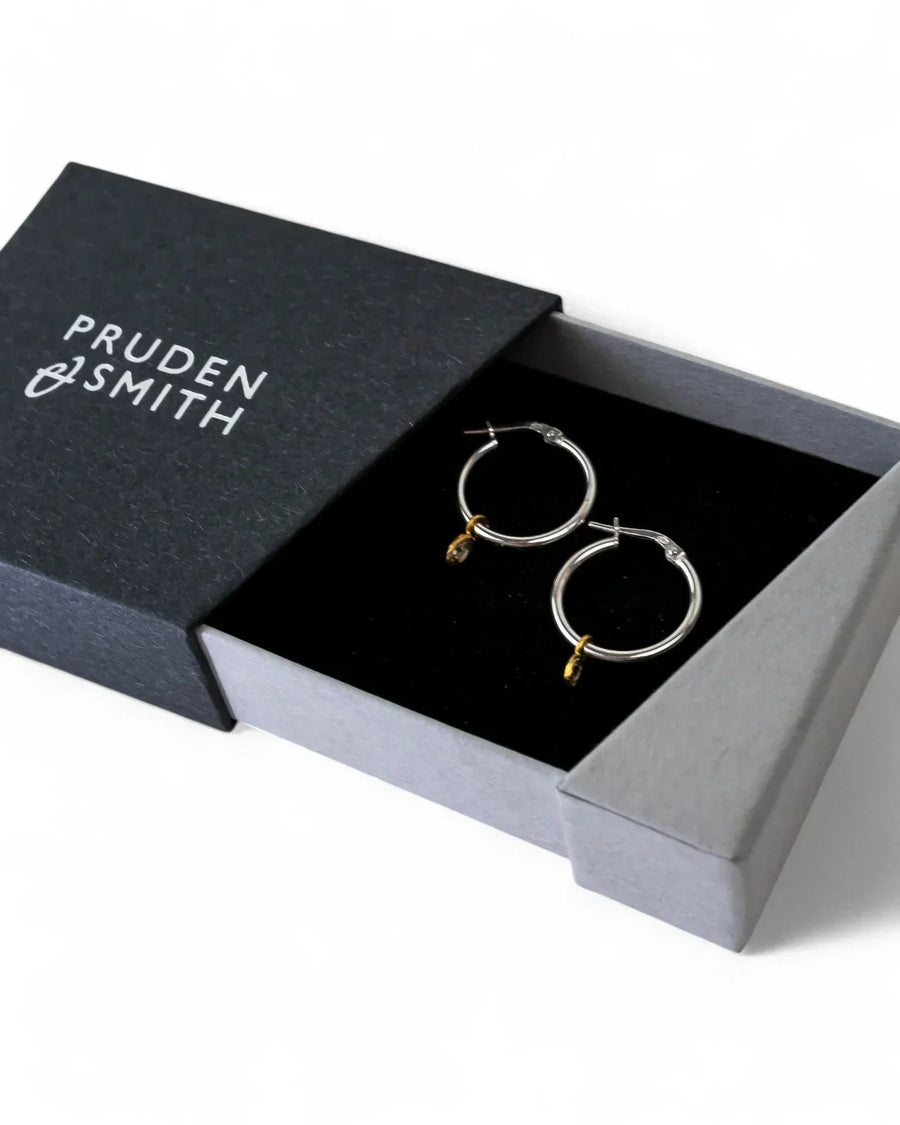 Silver hoop earrings with rough diamond drops in a black box.