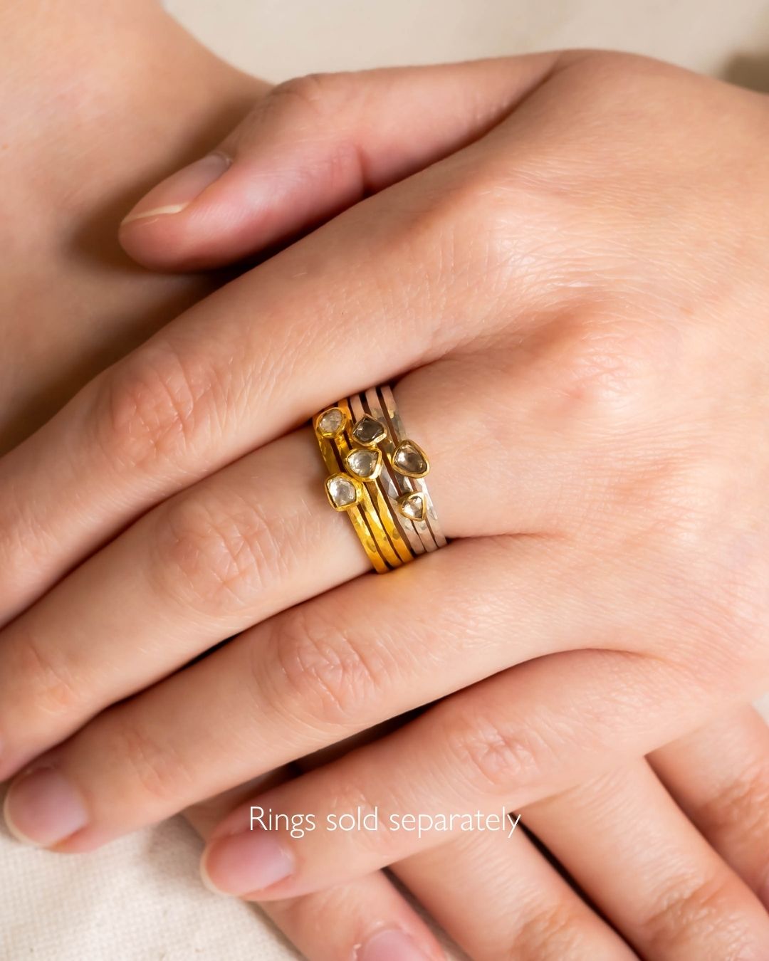 Gold and silver stacking rings with rough diamonds on a hand.