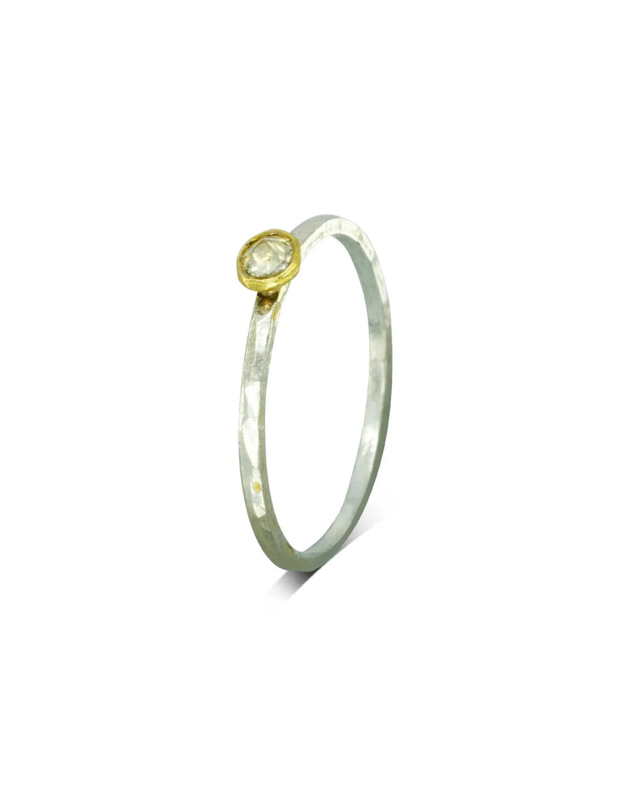 Silver stacking ring with a gold bezel setting holding a rough diamond.