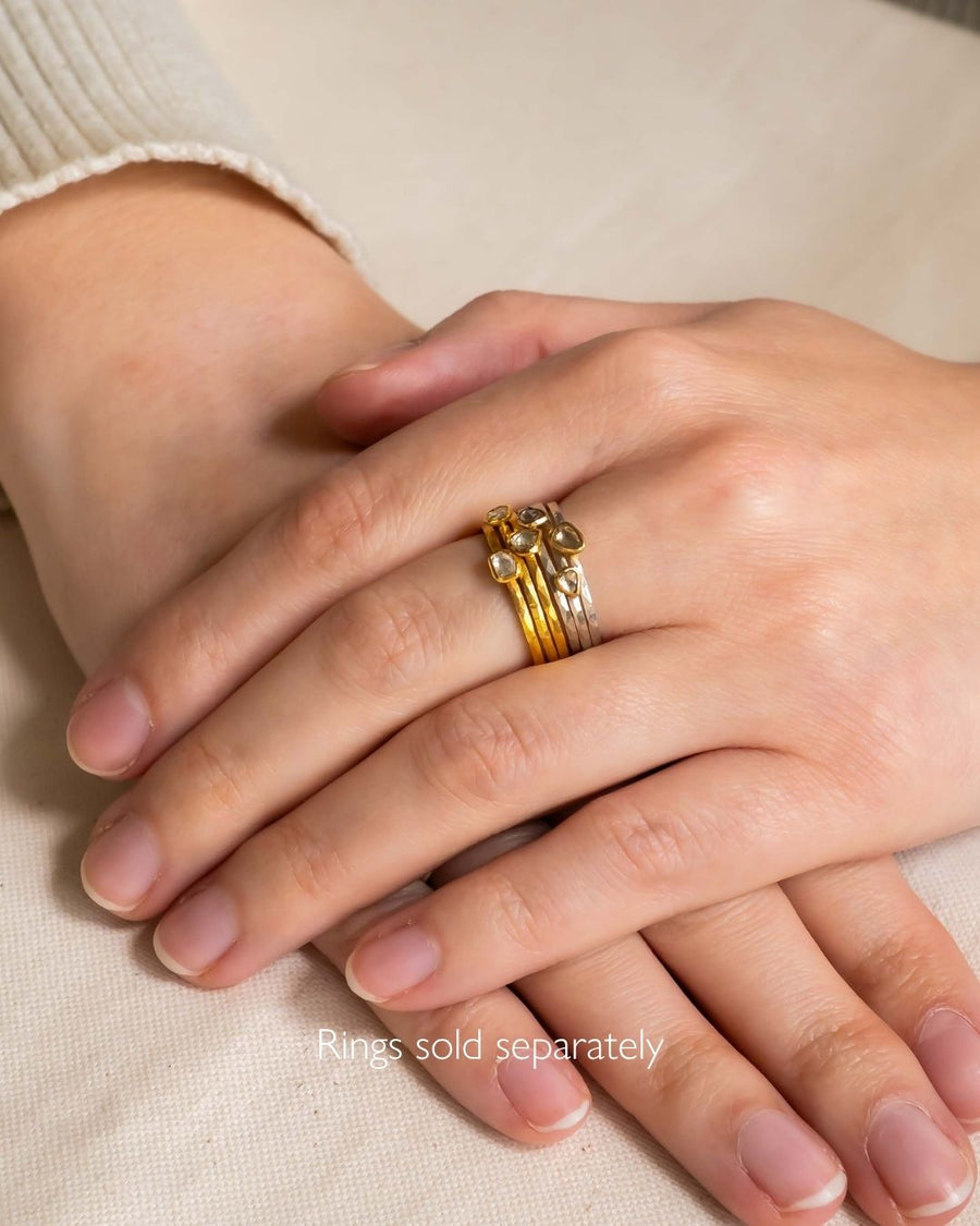 Gold and silver stacking rings with rough diamonds on a hand.