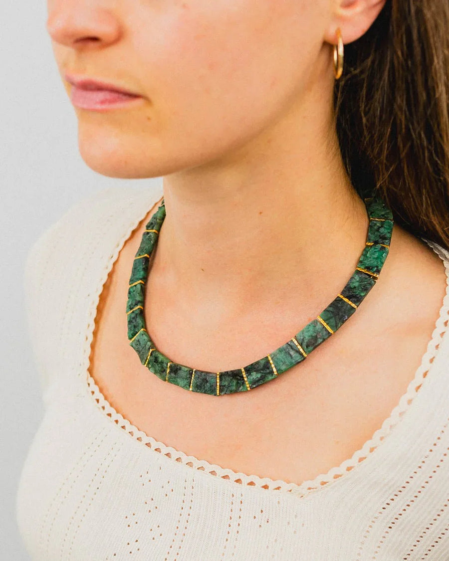 Woman wearing chunky rough emerald collar necklace with gold accents