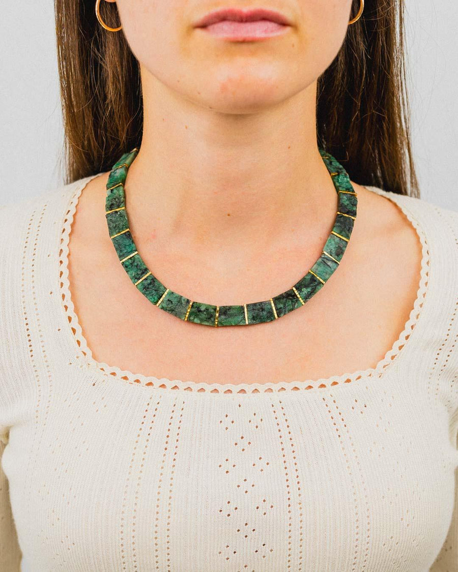 woman wearing a chunky rough emerald collar necklace with gold accents