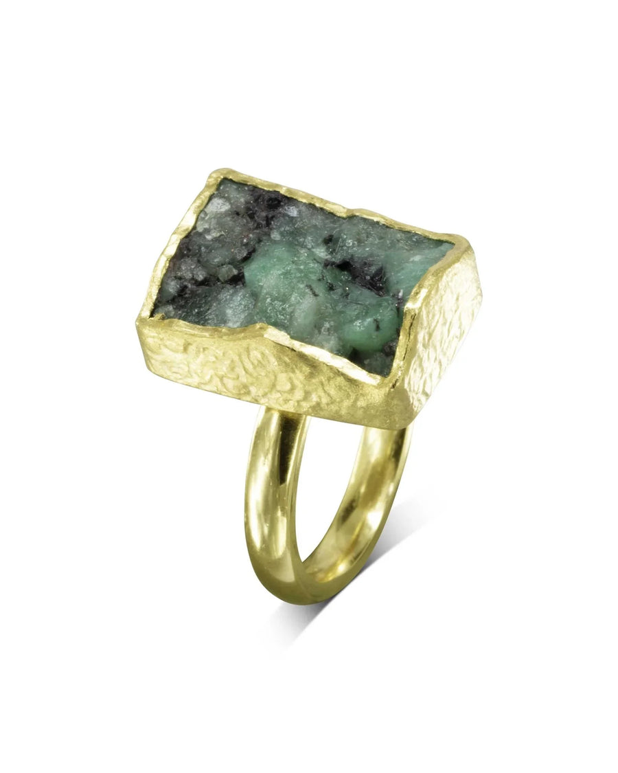 Gold ring with a rectangular rough emerald gemstone.