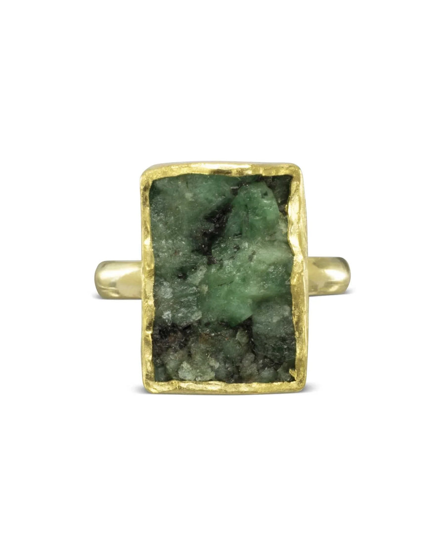 Gold ring with a rectangular, rough emerald gemstone.