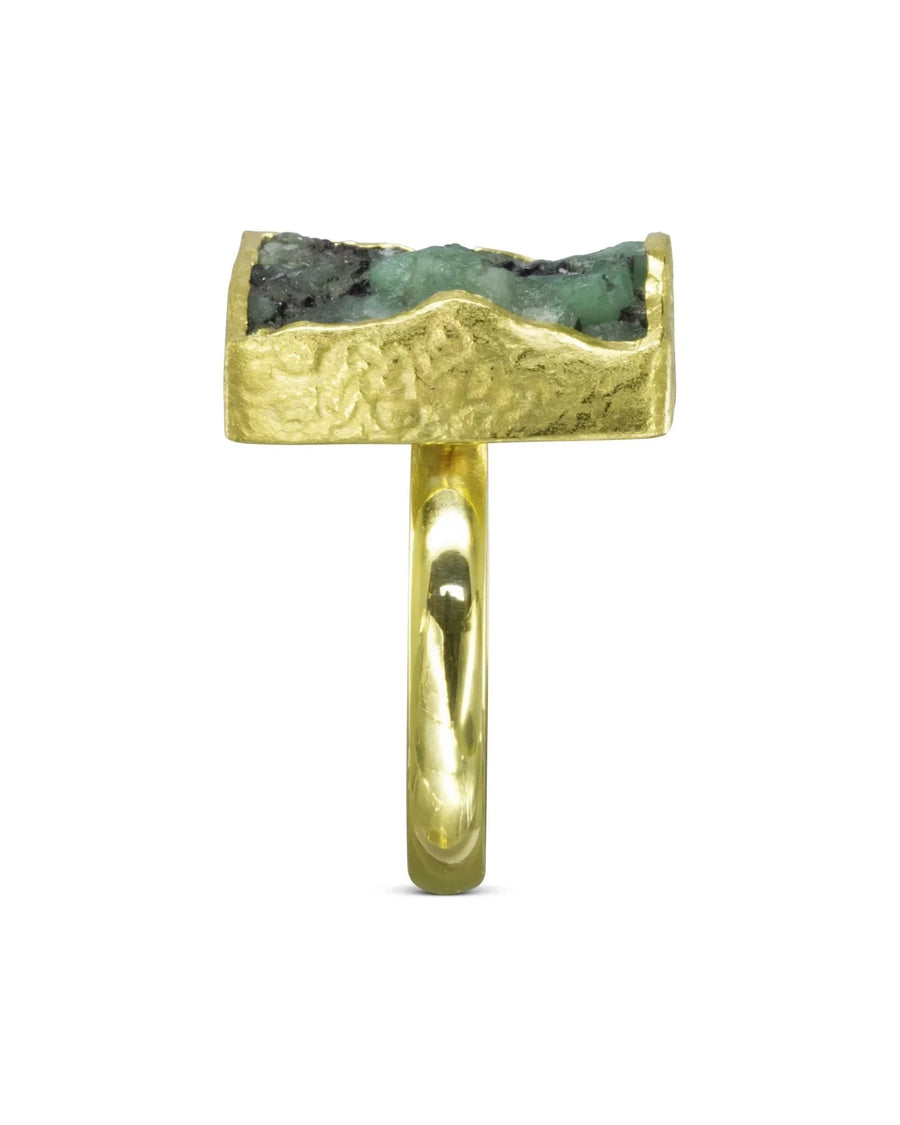 Gold ring with a rough, rectangular emerald gemstone.