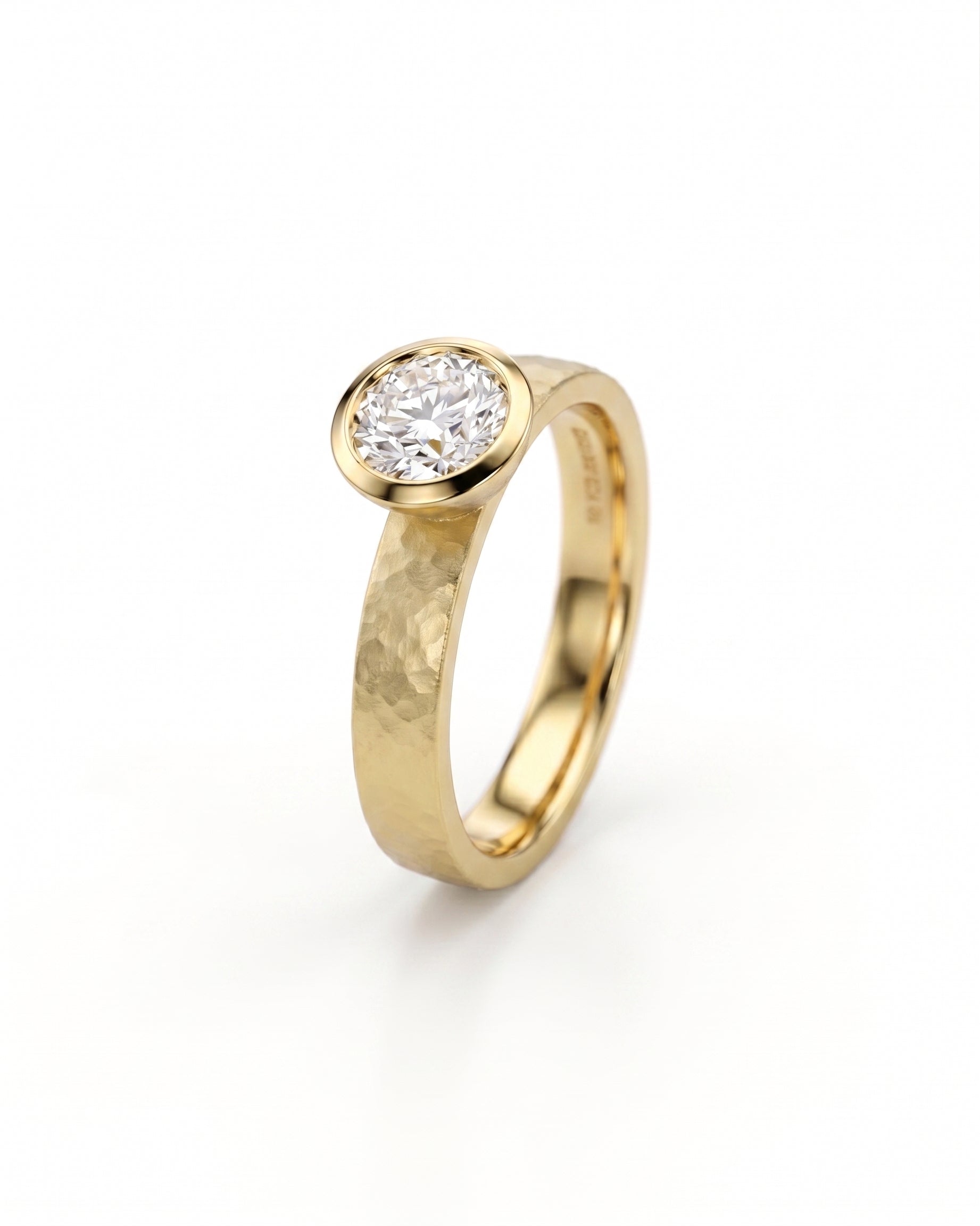 Gold hammered bezel engagement ring with a round brilliant cut diamond.