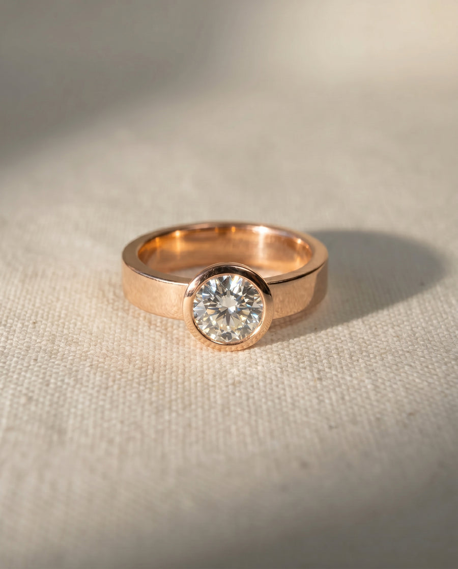 18ct rose gold engagement ring with a round brilliant cut diamond in a rough hammered bezel.