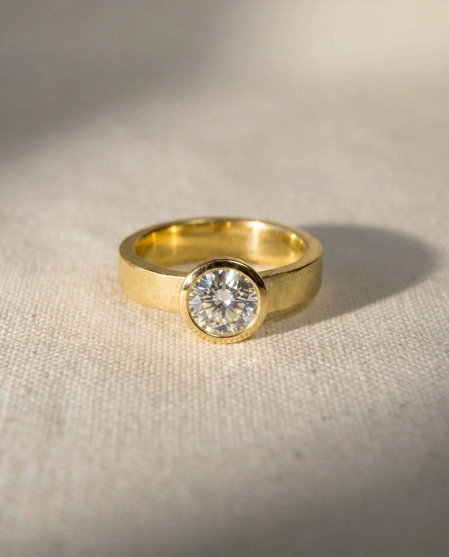 18ct yellow gold engagement ring with a round brilliant cut diamond in a rough hammered bezel.