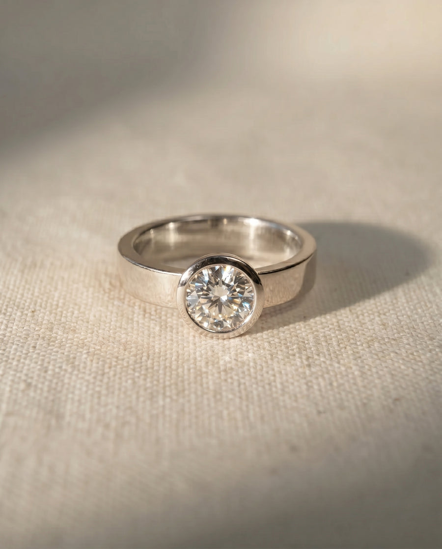 Platinum engagement ring with a round brilliant cut diamond in a rough hammered bezel.