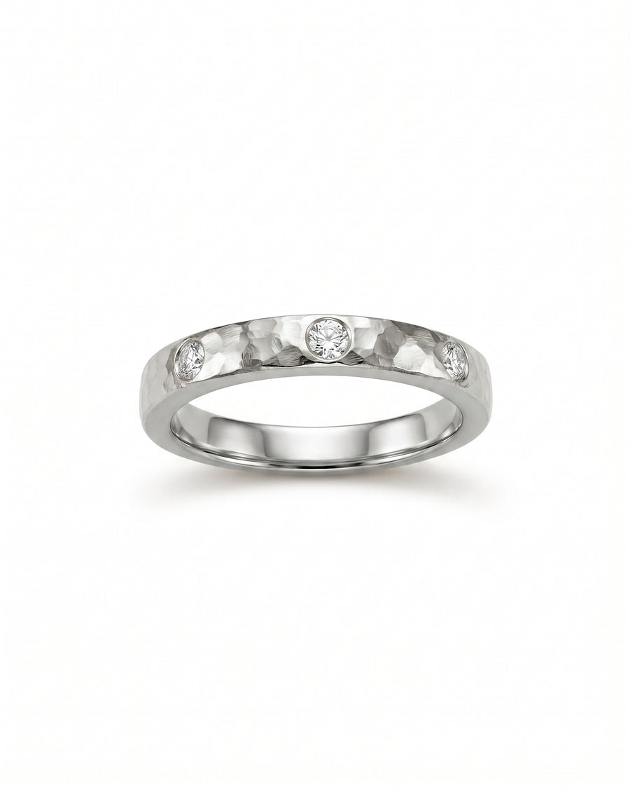 Silver rough hammered diamond ring with three inset diamonds.