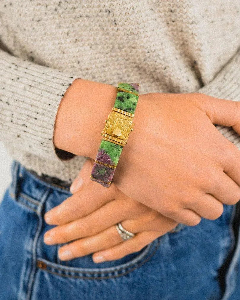 Hand wearing a rough ruby zoisite bracelet with gold textured clasp