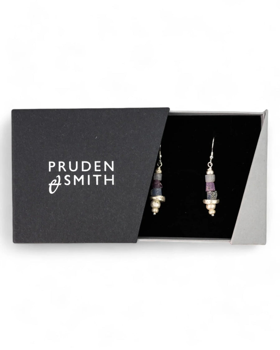 Silver earrings with rough sapphire gemstones and silver beads in a black gift box.