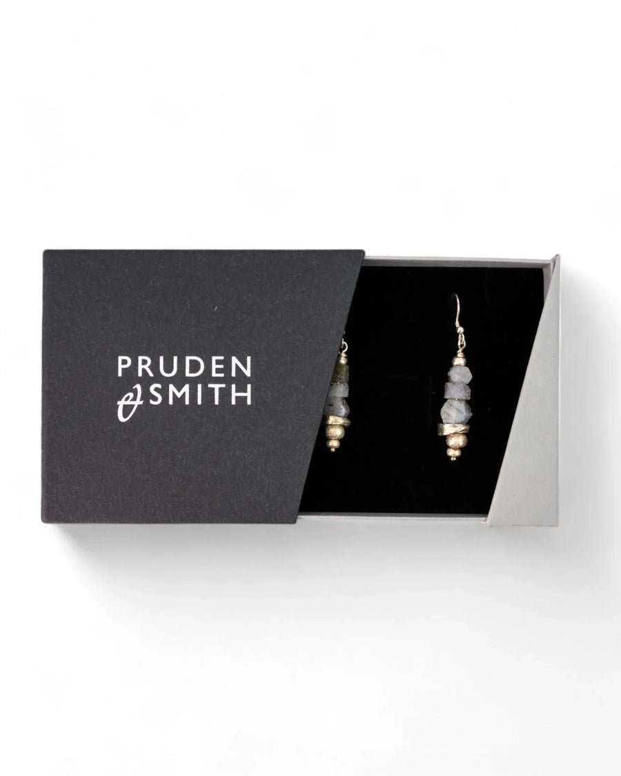 Silver earrings with rough sapphire stones in a black gift box.