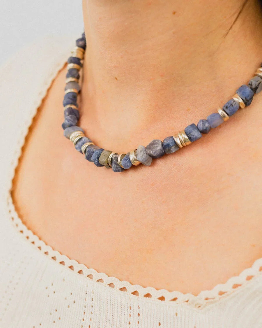 Handmade necklace with rough blue sapphires and silver discs on a woman's neck, artisan style