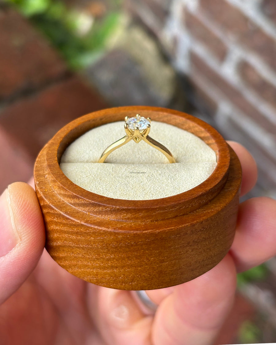 0.75ct round cut solitaire engagement ring with a six-claw setting in yellow gold inside a wooden box.
